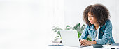 istock American teenage woman sitting in white office with laptop, she is a student studying online with laptop at home, university student studying online, online web education concept. 1433145639