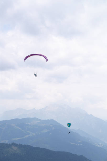 istock Two paragliders flying over mountains on a cloudy day. 1433147323