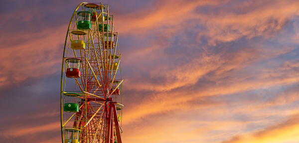 Attraction (carousel) ferris wheel against the background of a romantic evening sky