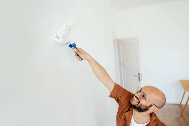 istock Smiling young man painting wall with paint roller 1433147559