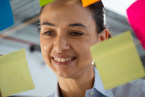Female office worker sticking post its onto glass.