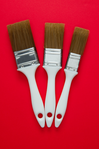 Paintbrushes on red background, directly above.