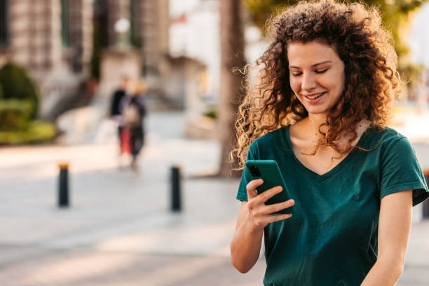 istock Young Woman Using Phone While Walking Down The Street 1433151401
