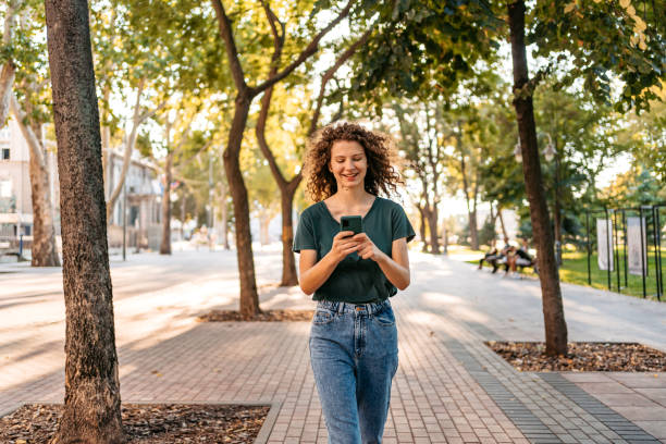istock Young Woman Using Phone While Walking Down The Street 1433151585