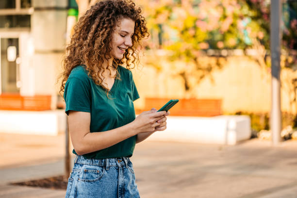 istock Young Woman Using Phone While Walking Down The Street 1433152352