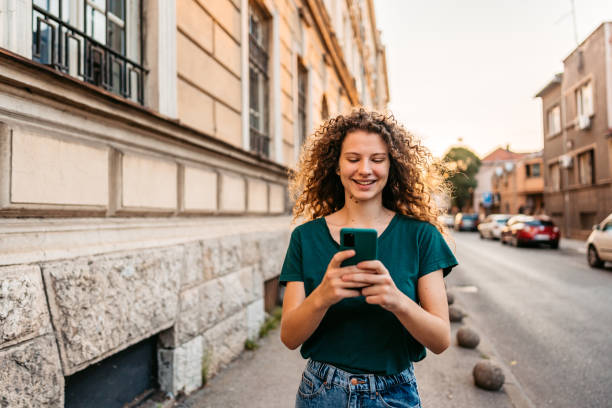 istock Young Woman Using Phone While Walking Down The Street 1433152379