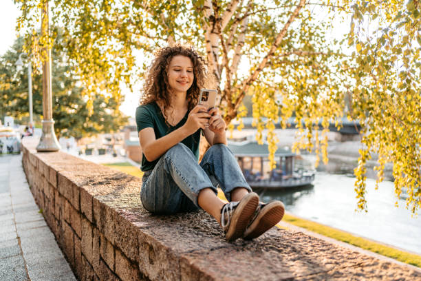 istock Young Woman Using Phone While Sitting On The Quayside 1433152399