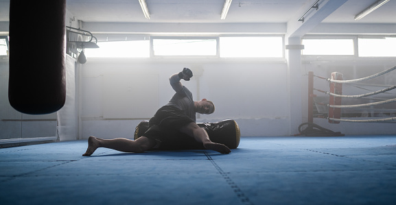 Male MMA fighter during training session with punching bag. Combat sport and healthy lifestyle concept.