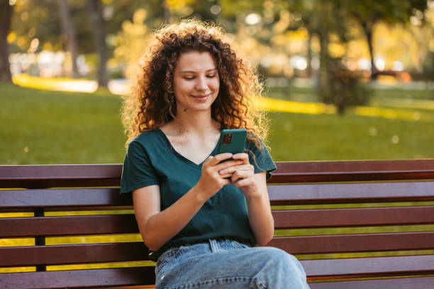 istock Young Woman Using Phone While Sitting On A Park Bench 1433152709