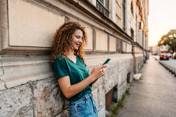 istock Young Woman Using Phone While Leaning On A Building Wall 1433152745