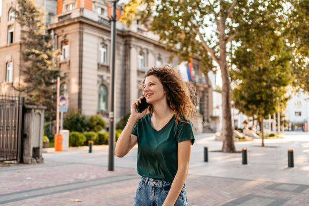 istock Young Woman Talking On The Phone While Walking Down The Street 1433153039