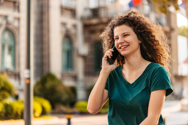 istock Young Woman Talking On The Phone While Walking Down The Street 1433153063