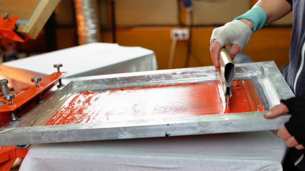 istock silk screen print. male hand with a squeegee. serigraphy production selective focus photo. printing images on clothes by silk screen method in a design studio 1433153218