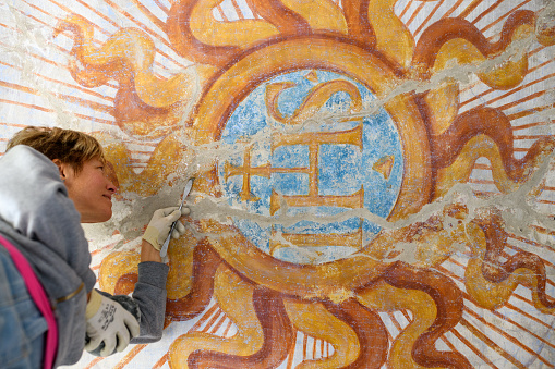 Professional restorer restoring antique chapel fresco in Italy