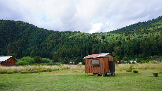 a tiny house in a country surrounded by mountains and  green forest