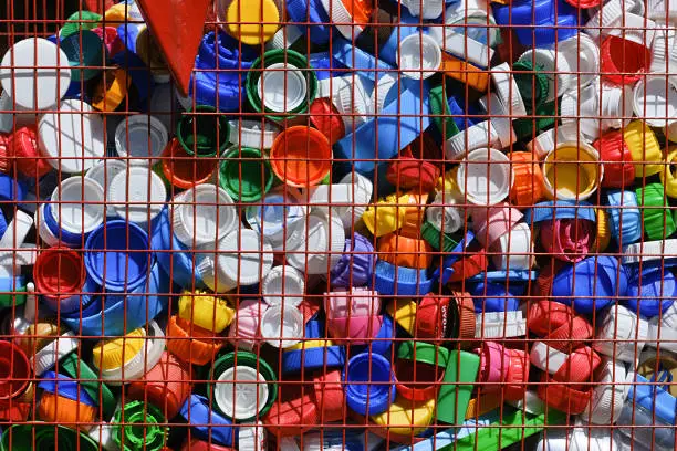 Container for collecting plastic lids. Separate collection of garbage. Colorful lids from plastic bottles.