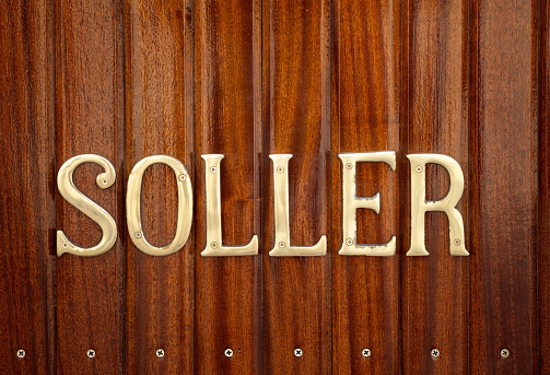 Brass lettering nameplate for Soller on mahogany tongue and groove boards on the side of the antique tram that travels between Soller and Port Soller in Majorca. Good copy space. The tram service that runs the 4.8km between Soller and the Port Soller opened in 1913.