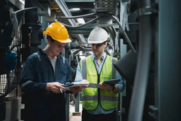 Photo of Engineer and team examining the air conditioning cooling system of a huge building or industrial site.