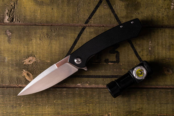 istock Pocket knife and flashlight on an army crate. Knife and lantern on the table. A sharp knife and a small lantern. 1433160725