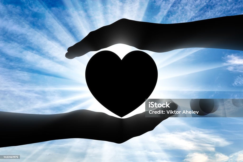 Altruism. Silhouette of hands protecting heart symbol. Altruism concept. Silhouette of hands protecting heart symbol Selfless Stock Photo
