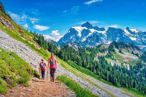 Mother and son hikes on the Chain Lakes Loop trail in Mount Baker Wilderness, Washington state, USA with Mount Shuksan in the background.
