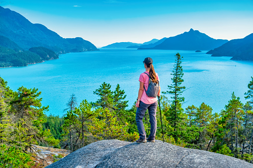 Woman looks at view with Howe Sound and the Coast Mountains in Murrin Provincial Park, BC, Canada.