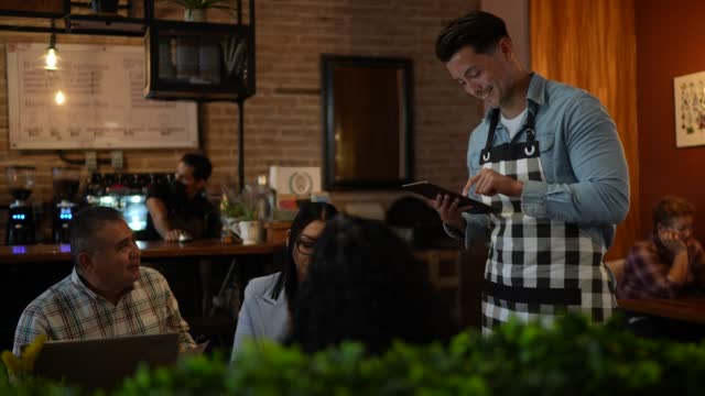 Waiter using digital tablet taking orders from coworkers in a restaurant