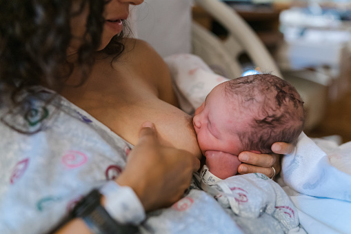 Cropped shot of an unrecognizable Eurasian woman breastfeeding her newborn baby while sitting in a hospital bed.