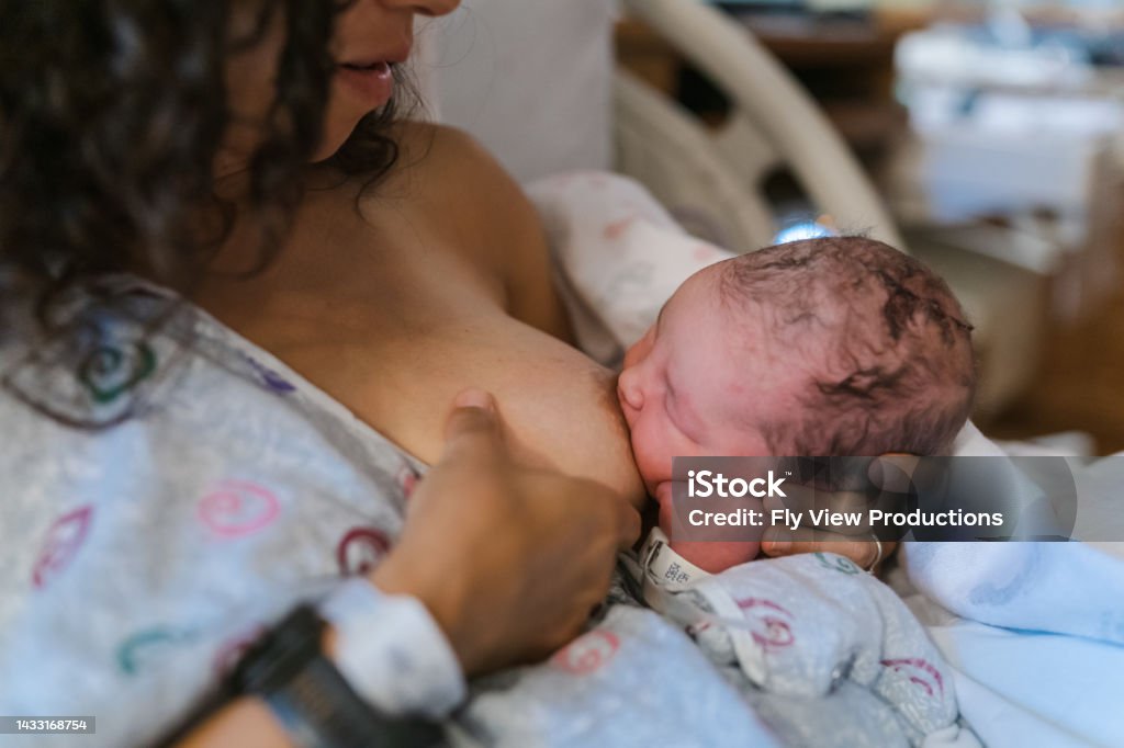 Newborn baby breastfeeding at the hospital Cropped shot of an unrecognizable Eurasian woman breastfeeding her newborn baby while sitting in a hospital bed. Breastfeeding Stock Photo