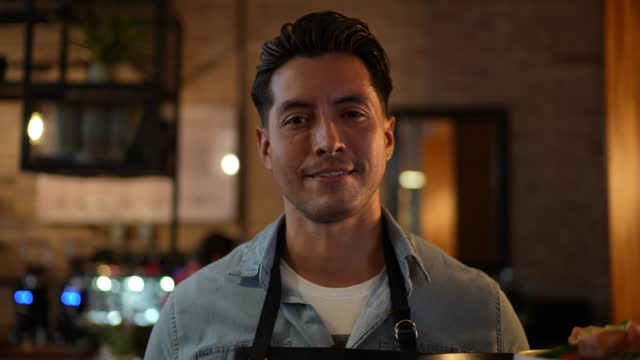 Portrait of mid adult waiter carrying a finished dish in a restaurant