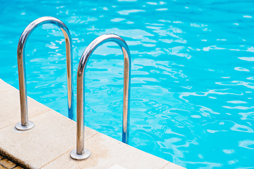 handrails of stairs for descent into the pool. the concept of summer holidays. means for water purification.