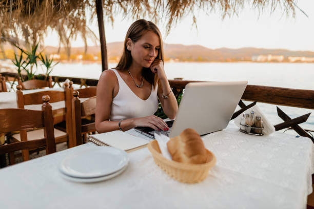 istock Woman learning and using a laptop in a restaurant at the seaside 1433174967