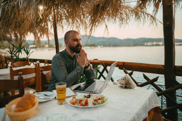 istock Man using a laptop in a seaside restaurant during a vacation 1433175066
