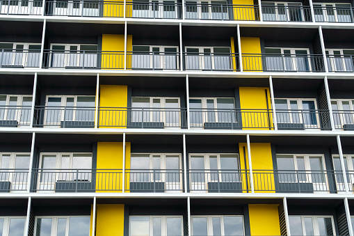 the facade of a modern multi-storey building, windows and balconies, yellow and black walls, the concept of urbanism and city construction