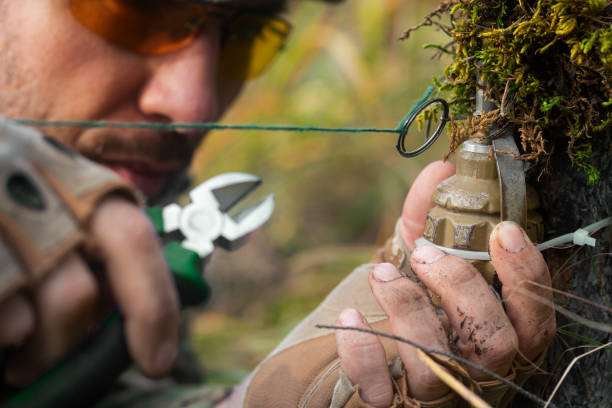 photo en gros plan - un sapeur efface un piège. les coupe-fils coupent le fil du piège à grenades à fragmentation. - hand grenade explosive bomb war photos et images de collection