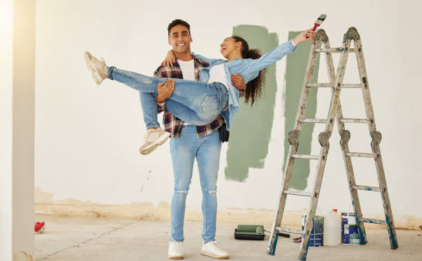 diy、リフォーム、壁画、幸せな夫婦が家を改装し、一緒に楽しんでいます。遊び心のある夫と妻は愚かで間抜けで、彼らの関係を楽しんでいて、一緒にプロジェクトします - female house painter home decorator paintbrush ストックフォトと画像