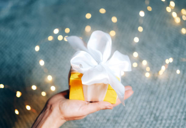 istock Woman's hand holding yellow Christmas present box. 1433189007