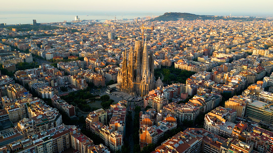 Aerial view of Barcelona city skyline and Sagrada Familia Cathedral at sunrise. Eixample residential famous urban grid. Cityscape with typical urban octagon blocks. Catalonia, Spain