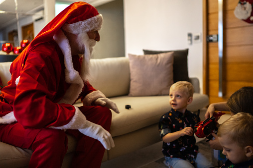 Santa Claus giving Christmas present to children at home