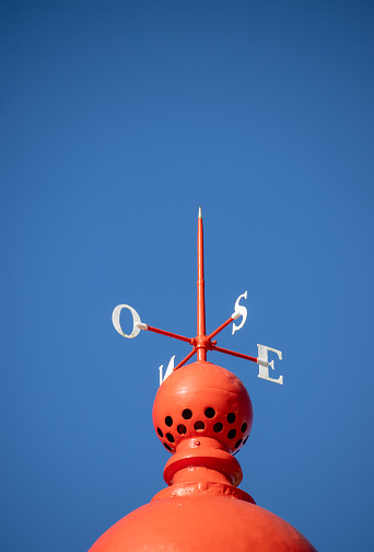Red compass indicating wind direction in north, south, east, west with a blue sky background