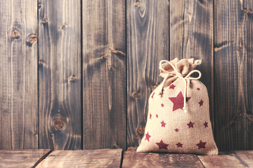 Hanger Christmas bags with christmas decorations on wooden wall.