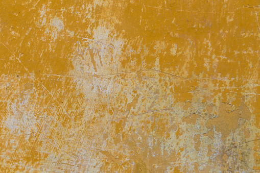 Abstract yellow, painted wall with gouges, scratches and prominent brush strokes.