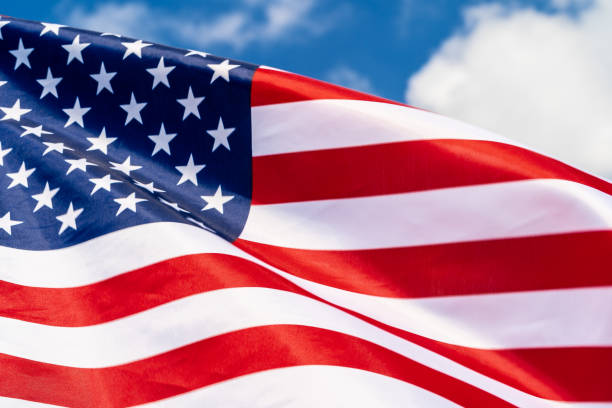 istock American flag on flagpole waving in the wind against white clouds 1433195397