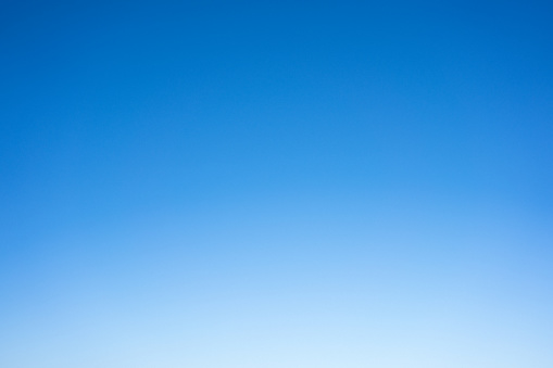 A photograph of a clear blue daytime sky, with the brightness increasing towards the horizon.