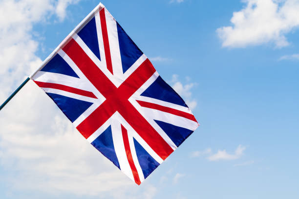 istock United Kingdom Flag waving on wind in blue sky 1433199445