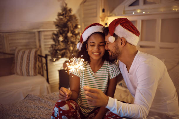 istock Young loving couple using sparklers on Christmas Eve at home. 1433199496