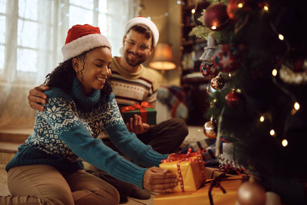istock Happy couple arranging wrapped gift boxes under the Christmas tree. 1433199664