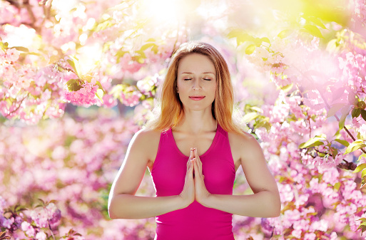 Close-up portrait of meditating woman against blooming trees background