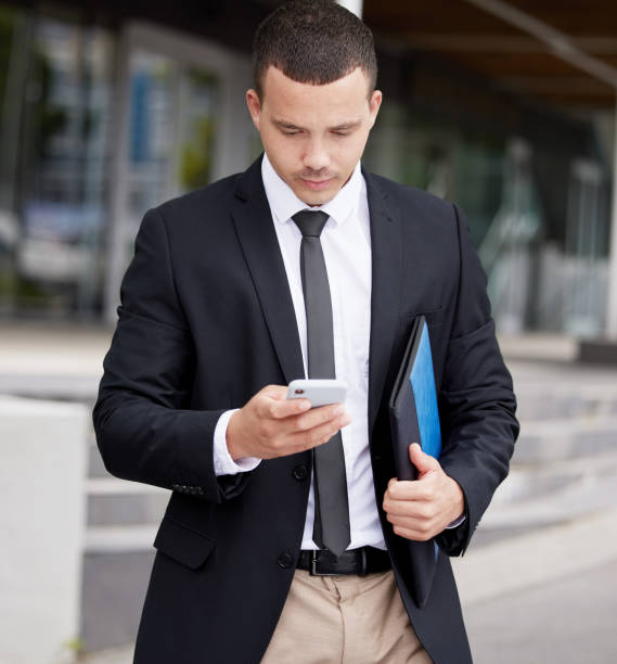 istock A handsome young mixed race business man using his cellphone while walking through the city on his way to work. Young and confident corporate professional checking messages during his morning commute 1433203397