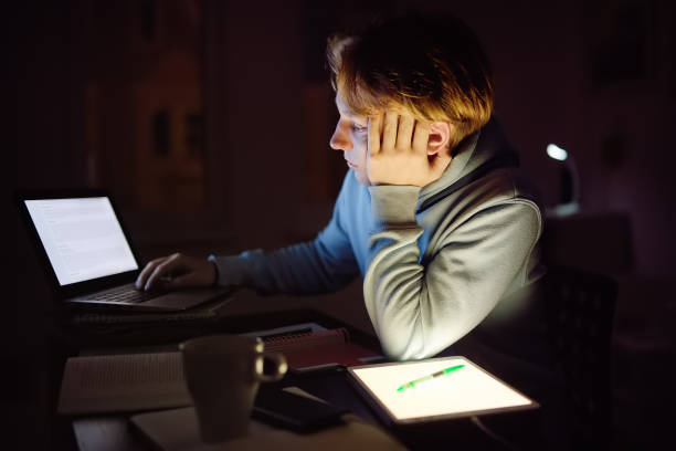 istock Tired teenager napping while studying at home with laptop and tablet pc at night. Online learning, distance lessons, freelance - modern lifestyle young man working late night at home office 1433204033